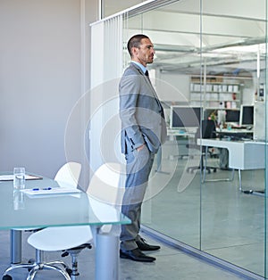 Hes a corporate heavyweight. a handsome businessman standing in his office.