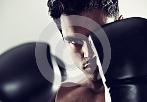 Hes dedicated to the sport of boxing. Closeup portrait of a young male boxer in a fighting stance.