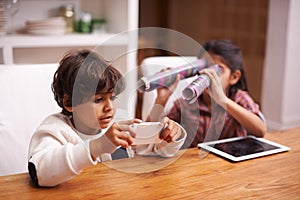 Hes going for a highscore... shes trying to distract him. Shot of two siblings having fun at home.