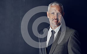 Hes got all the attributes of a great CEO. Studio portrait of a mature businessman against a dark background.