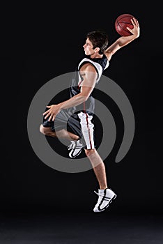 Hes got basketball superpowers. Full length profile shot of a young male basketball player in action against a black