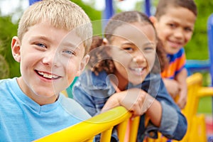 Hes got fantastic friends. A multi-ethnic group of happy children playing on a jungle gym in a play park.