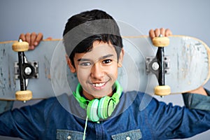 Hes got street style. A portrait of a happy young boy holding his skateboard.