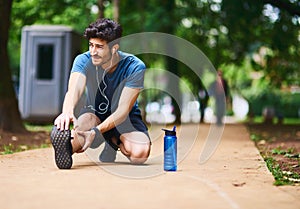 Hes got unfaltering determination to succeed on his fitness goals. a sporty young man stretching his legs while