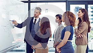 Hes a great leader. a group of businesspeople working on a whiteboard in the boardroom.