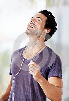 Hes a happy go lucky kinda guy. a handsome man laughing with his earphones in listening to music.