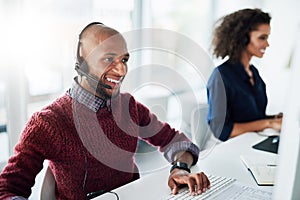 Hes happy to help. a handsome young male call center agent working in his office.