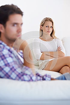 Hes hard to comprehend - relationship issues. An annoyed woman sitting on a couch with arms crossed and looking at her