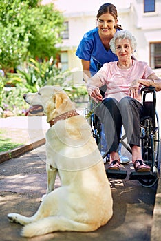 Hes her most trusted friend. a resident, her dog and a nurse outside in the retirement home garden.