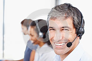 Hes here to answer all your questions. Closeup portrait of a call center professional with colleagues seated in the