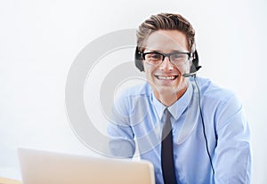 Hes here to help. Portrait of a smiling businessman wearing a headset.