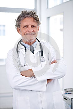 Hes a hero of health. Portrait of a smiling mature doctor standing in his office.