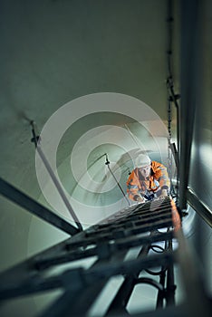 Hes on his way to a promotion. Shot of a young engineer in safety gear climbing a ladder.