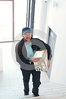 Hes making his way to the top floor. Full length shot of a handsome delivery man heading up a flight of stairs with a