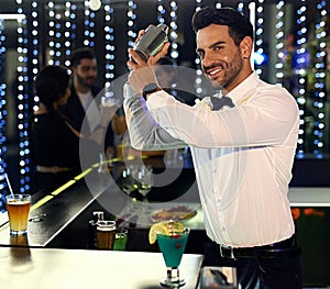 Hes a mixology master. Portrait of a barman mixing drinks behind the bar in a nightclub.