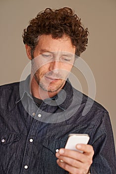 Hes the modern man. a handsome young sending a text message on his mobile phone.