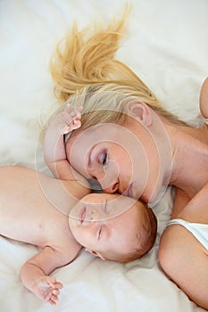 Hes my whole world. High angle shot of a mother with her eyes closed and her newborn child lying in bed.