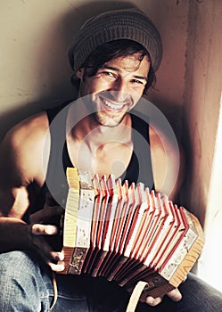 Hes not your convential musician. Handsome young man playing an accordian with a smile.