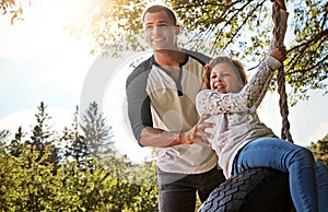 Hes a positive influence in his daughters life. a happy father pushing his daughter on a tyre swing.