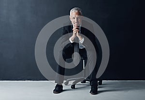 Hes a prime example of professional success. Studio portrait of a mature businessman against a dark background.