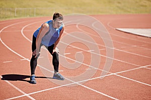 Hes ready to race. Shot of a handsome young runner out on the track.