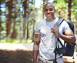 Hes a real outdoorsman. A handsome african man standing outdoors in the forest.