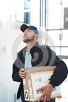 Hes on route to make a delivery. Shot of a handsome delivery man heading up a flight of stairs with a customers order.