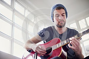 Hes a self-taught muso. a handsome young man playing a guitar at home. photo