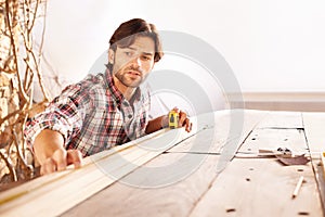 Hes a skilled carpenter. A handsome young carpenter measuring and marking wood.