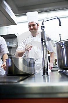 Hes a skilled saucier. chefs preparing a meal service in a professional kitchen.