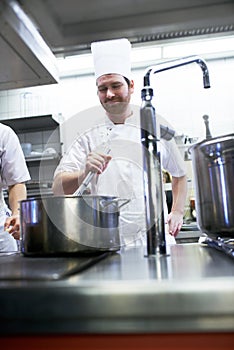 Hes a skilled saucier. chefs preparing a meal service in a professional kitchen. photo