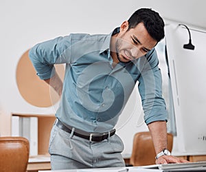 Hes starting to feel the strain of sitting too long. a young businessman experiencing back pain while working in an