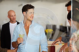 Hes starting to stutter - Feeling tipsy. A handsome young man drinking wine at an office social. photo