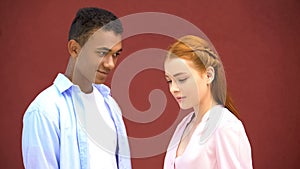 Hesitant mixed-race boy looking at beautiful red-haired girl, embarrassment