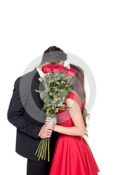 heterosexual couple kissing and covering faces with bouquet