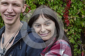 A heterosexual couple in love in front of a hedge. The young man