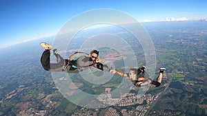 A heterosexual couple of skydivers kiss while free falling, on a summer day.