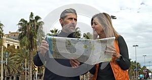 Heterosexual couple in their 40s tourists looking at a map in a city during vacation
