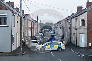 Police with vans close of a street with terraced houses to deal with an incident.  Residential setting