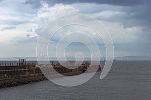 Heugh breakwater pier in stormy, cloudy weather with wind farm behind