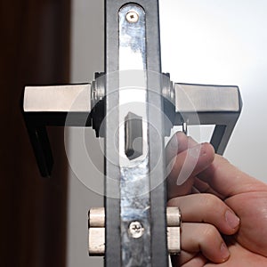 Hex key and installation of door lock and handle, close-up of installation work.