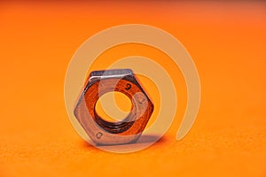 Hex nuts on orange background. Bolted connection elements