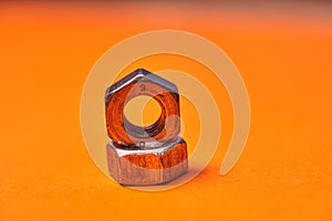 Hex nuts on orange background. Bolted connection elements