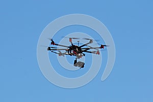 Hexacopter drone with camera in action on blue sky photo