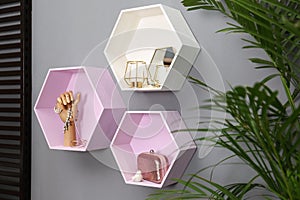 Hexagon shaped shelves with different stuff on wall. Interior design