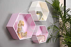 Hexagon shaped shelves with different stuff on wall. Interior design