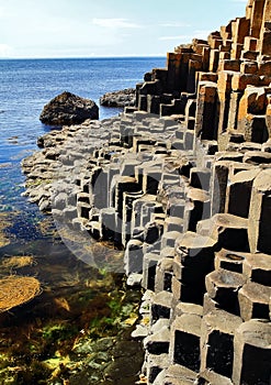 The hexagonal Basalt slabs of Giants Causeway dipping into the sea photo
