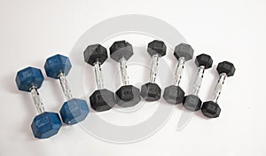 Hexagonal dumbbells of different weights, on a white photo