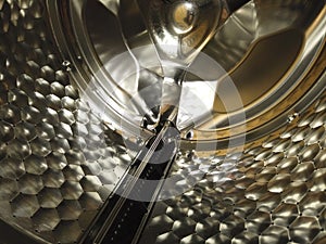 Hexagonal grid on the shiny metal surface of washing machine drum