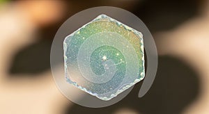 A hexagonal soap bubble capturing iridescent colors, surrounded by